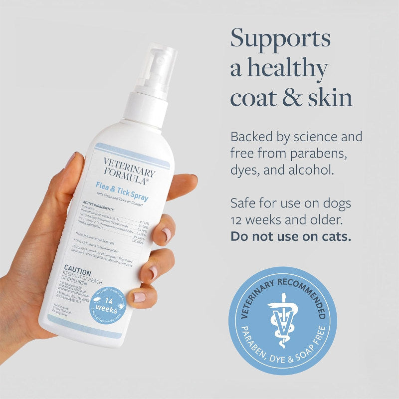 Hand holding a bottle of Veterinary Formula Flea & Tick Spray with product details on a light gray background.