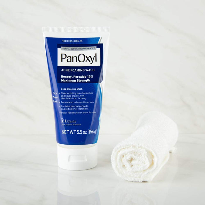 PanOxyl Acne Foaming Wash Maximum Strength bottle next to a rolled up towel, on top of a marble sideboard