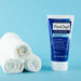 PanOxyl Acne Creamy Wash Benzoyl Peroxide 4% Daily Control, 6  oz bottle next to 3 towels in front of a green background